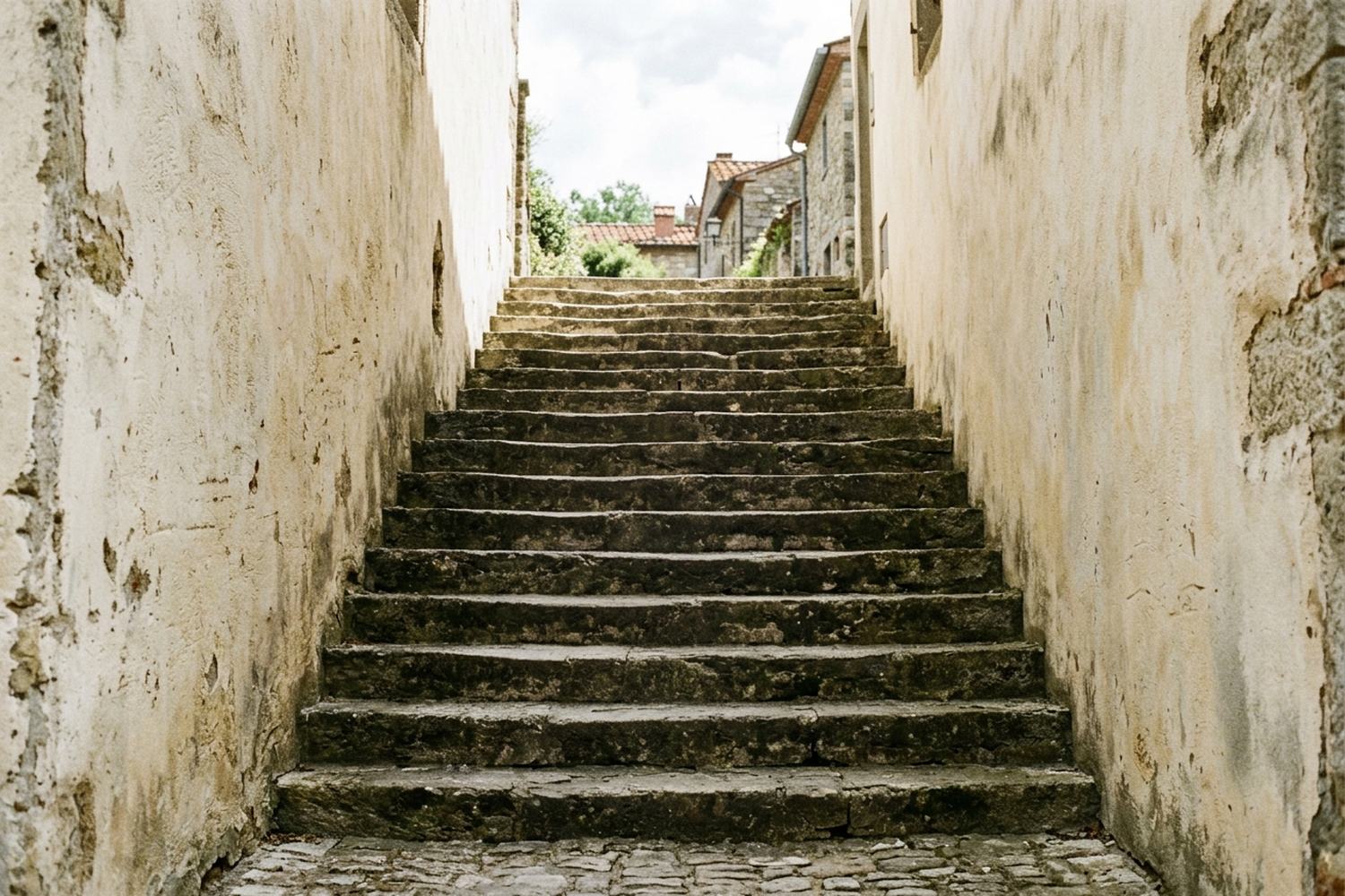A broad flight of worn stone steps rising between two walls into daylight.